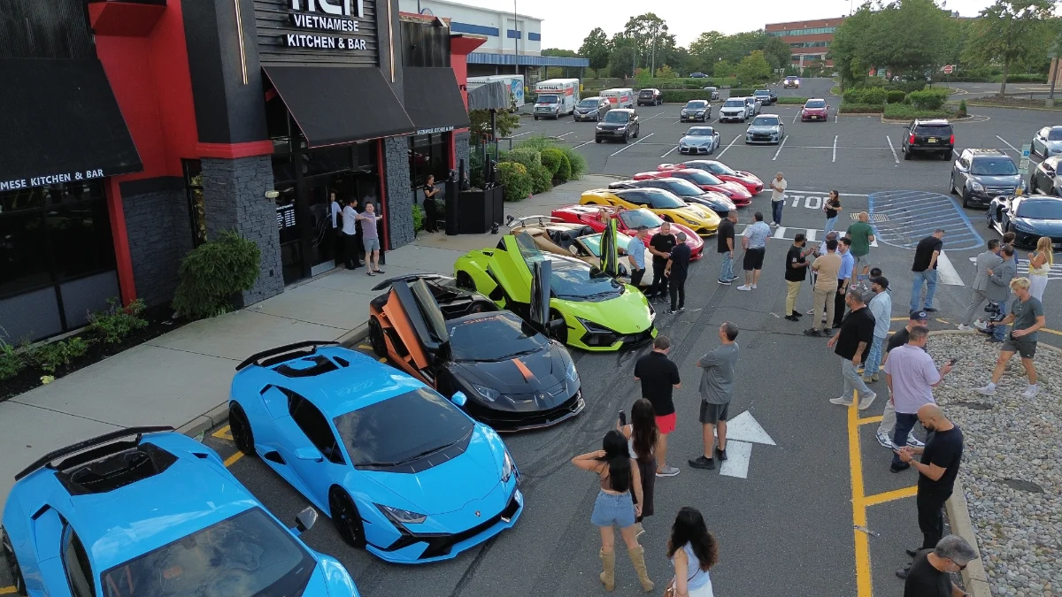 Colorful sports cars and visitors gathered outside a venue.
