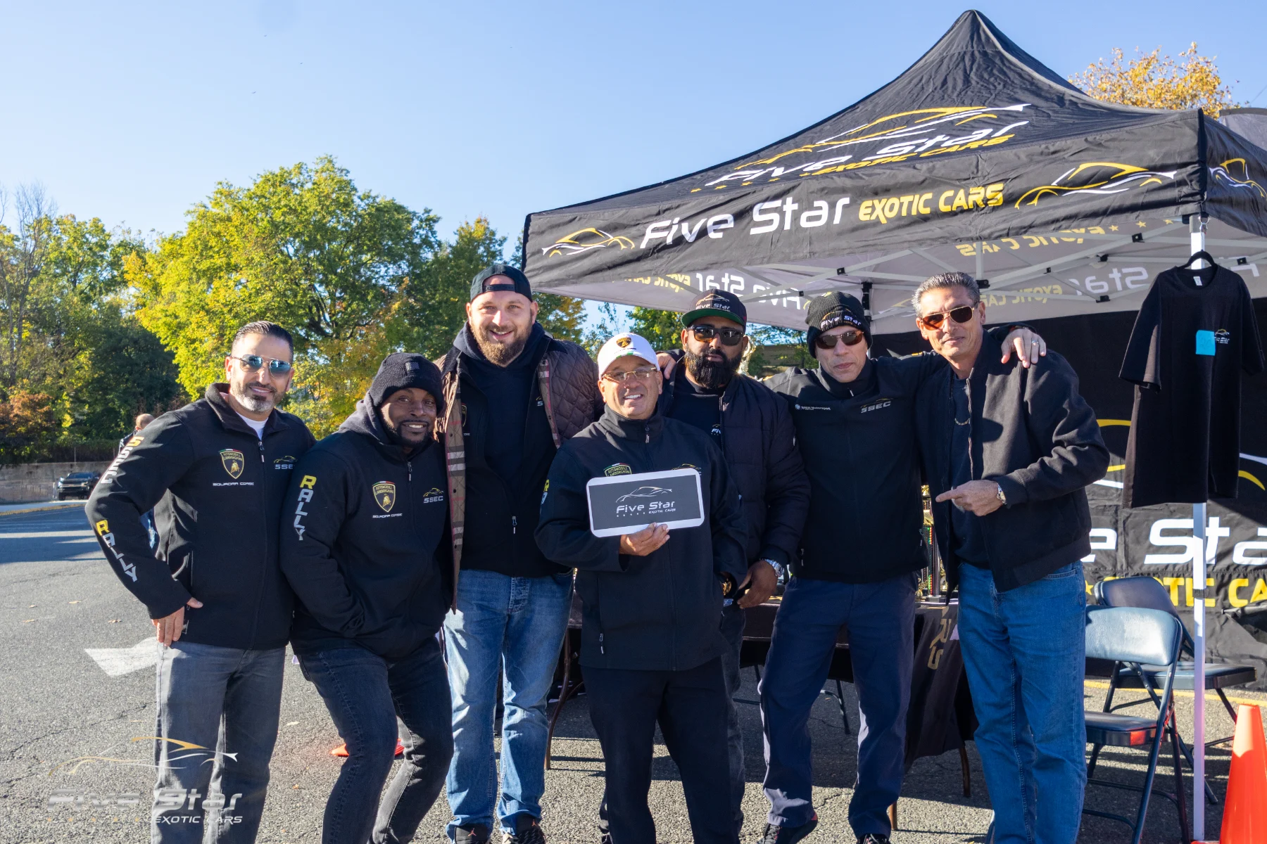 Members standing together in front of the Five Star Exotic Cars club tent.
